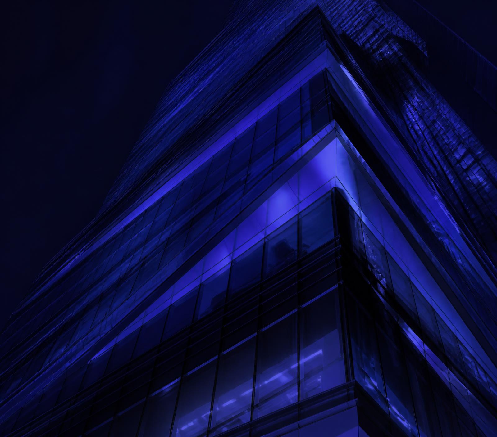 Layered glass tower facade lit in indigo at night